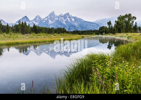 Den Grand Teton mit einer friedlichen Reflexion über den Fluss, aber mit viel Rauch aus einem in der Nähe von Waldbrand Stockfoto