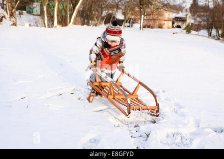 Kind Junge auf einem Schlitten Spaß im Schnee Stockfoto