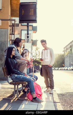 Schülerinnen und Schüler warten an der Bushaltestelle Stockfoto