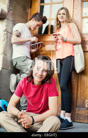 Porträt von Teenager mit Freunden im Hintergrund am Eingang der Universität Stockfoto