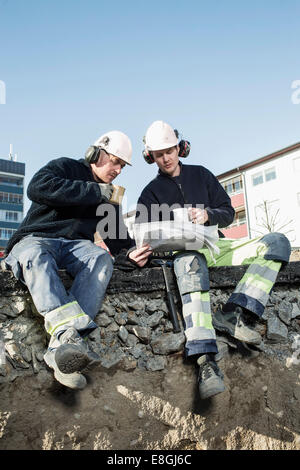 Bauarbeiter, die Blaupause beim Kaffeetrinken am Standort Analyse Stockfoto