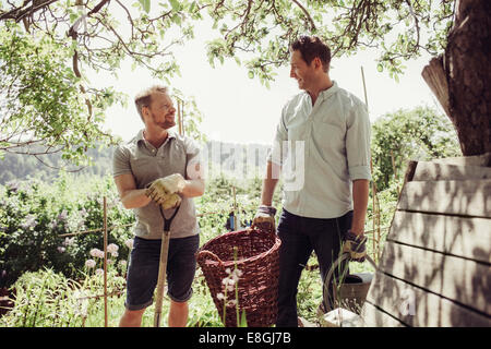 Lächelnde Männer sprechen bei der Gartenarbeit am Hof Stockfoto