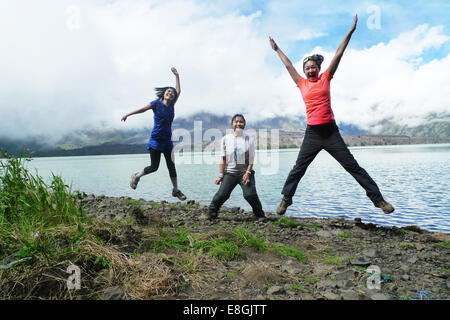 Drei glückliche Frauen springen an einem See, Mount Rinjani, Mataram, West Nusa Tenggara, Indonesien Stockfoto