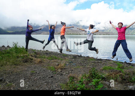 Fünf glückliche Frauen springen an einem See, Mount Rinjani, Mataram, West Nusa Tenggara, Indonesien Stockfoto