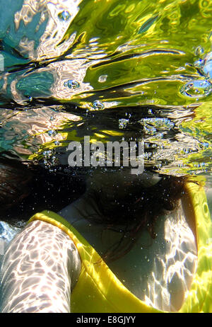 Nahaufnahme einer Frau in einem Kleid, die unter Wasser schwimmt, Sounion, Lavreotiki, Griechenland Stockfoto