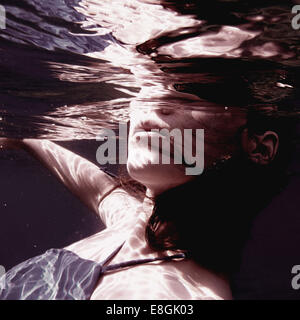 Nahaufnahme einer Frau in einem Kleid, die unter Wasser schwimmt, Sounion, Lavreotiki, Griechenland Stockfoto