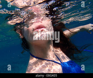 Nahaufnahme einer Frau in einem Kleid, die unter Wasser schwimmt, Sounion, Lavreotiki, Griechenland Stockfoto