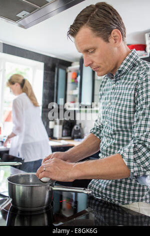 Mann Frau Reinigungsutensilien im Hintergrund bei Küche kochen Stockfoto