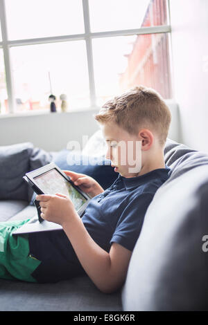 Seitenansicht eines jungen mit digital-Tablette zu Hause auf sofa Stockfoto