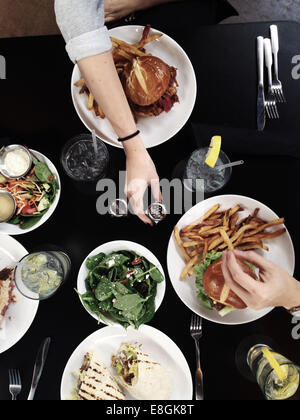 Menschen, die genießen Burger und Wraps mit Salat Stockfoto