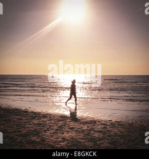 Frau zu Fuß am Strand bei Sonnenuntergang Stockfoto