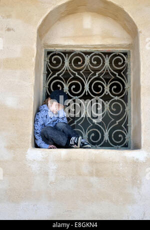 Stockholm, Schweden ein traurig und müde Junge sitzt In einem Fenster Tresor ein Sommertag Stockfoto