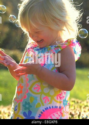 Glückliches Mädchen, das mit Seifenblasen im Garten spielt Stockfoto