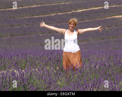 Frau mit ausgestreckten Armen stehend im Lavendelfeld, Provence, Frankreich Stockfoto