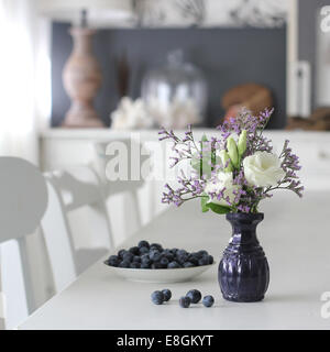 Vase mit Blumen und Schüssel mit Heidelbeeren Stockfoto