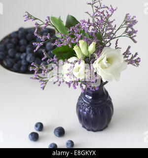 Vase mit Blumen und Schüssel mit Heidelbeeren Stockfoto