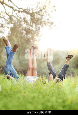 Drei Kinder im Rasen mit ihren Beinen in der Luft liegen Stockfoto