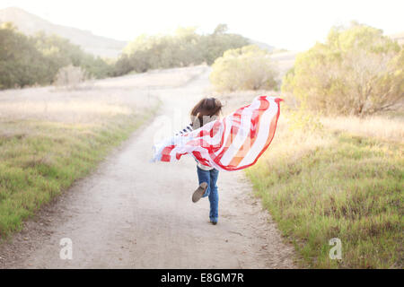 Rückansicht von Girl Running entlang eines Fußweges mit einer amerikanischen Flagge, USA Stockfoto