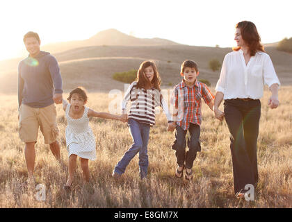 Fünfköpfige Familie Hand in Hand, Wandern in Wiese Stockfoto