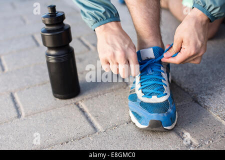 Geringen Teil der Mann Sport Schnürsenkel binden, durch die Wasserflasche auf Straße Stockfoto
