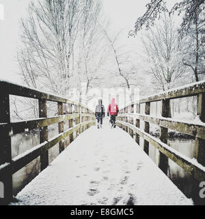 Rückansicht von zwei Kindern, die im Schnee über den Steg laufen Stockfoto