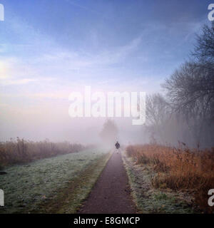 Rückansicht eines Mannes, der am nebeligen Morgen den Weg hinunter geht Stockfoto