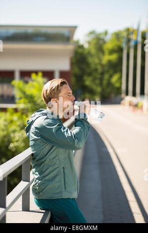 Seitenansicht des Fit Man Trinkwasser auf Brücke Stockfoto