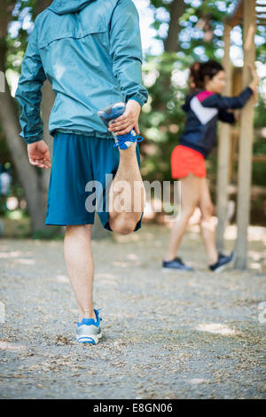 Hinten Blick niedrigen Abschnitt des Mannes im Outdoor-Fitness-Studio trainieren, mit Frau im Hintergrund Stockfoto