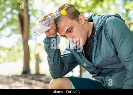 Müde Menschen keuchend gedrückter Wasserflasche nach Training im park Stockfoto