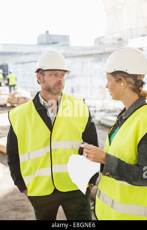 Männliche und weibliche Architekten diskutieren auf Baustelle Stockfoto