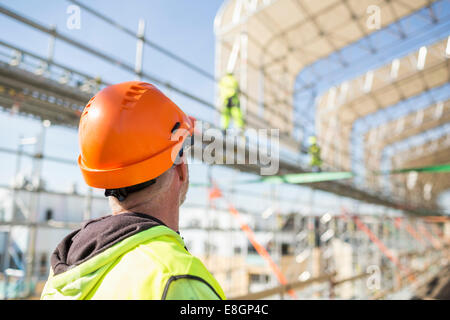 Rückansicht des Arbeiters Blick auf Kolleginnen und Kollegen arbeiten auf Baustelle Stockfoto