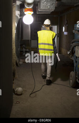 Voller Länge Rückansicht des weiblichen Bauarbeiter in beleuchteten Raum Stockfoto