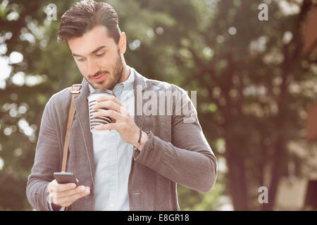 Junger Geschäftsmann Kaffeetrinken mit smart-Phone im freien Stockfoto