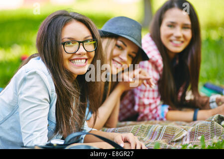 Teenager-Mädchen mit ihren Freundinnen auf dem Rasen liegend Stockfoto