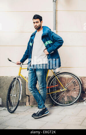 In voller Länge Portrait von zuversichtlich Mann mit Fahrrad auf Bürgersteig Stockfoto