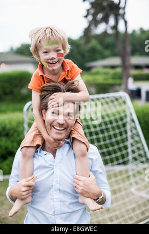 Porträt der glückliche Vater tragen verletzte junge auf Schultern Stockfoto