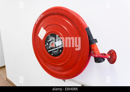 Rot Feuerwehrschlauch an Wand Gebäudeinneren. Stockfoto