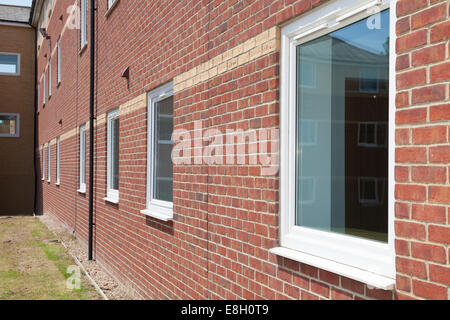 Perspektive der weißen Fenster in roten Backsteinmauer auf kommerzielle Gebäude. Stockfoto