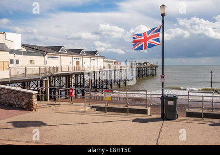 Die Pier erstreckt sich auf das Meer in Teignmouth, Devon mit einem Union Jack flattern im Vordergrund. Stockfoto