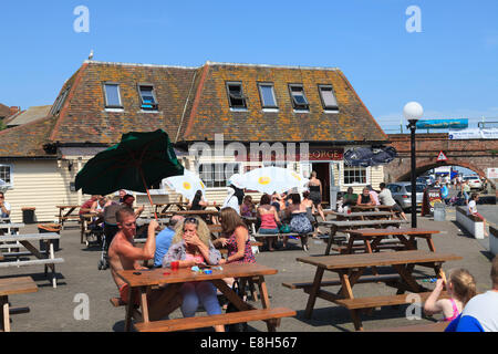 Menschen genießen den Sonnenschein im Sommer vor der Royal George Pub in der Nähe des Hafens in Folkestone. Stockfoto