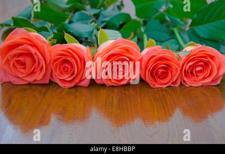 Fünf Rosen auf einer hölzernen Tischplatte Stockfoto