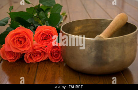 Klangschale auf Holzoberfläche in der Nähe von Rosen Stockfoto