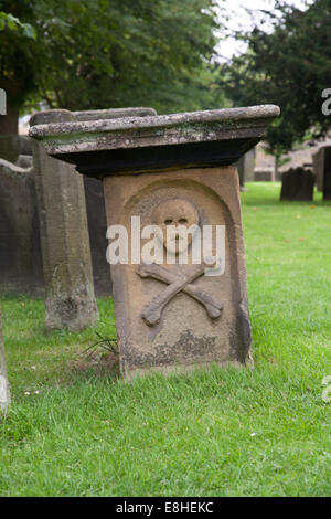 Friedhof der Kirche von Eyam Derbyshire Peak District England Großbritannien zeigen Pest Grabstein mit Schädel und gekreuzten Knochen Stockfoto