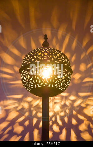 Vertikale Nahaufnahme von einem traditionellen Metall Lampenschirm Schattenwurf an der Wand in den Souks von Marrakesch. Stockfoto