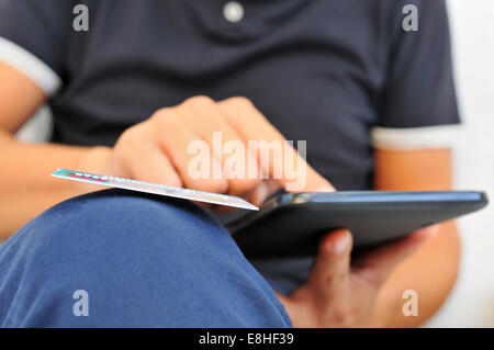 ein junger Mann, Online-shopping mit Kreditkarte über einen Tabletcomputer Stockfoto