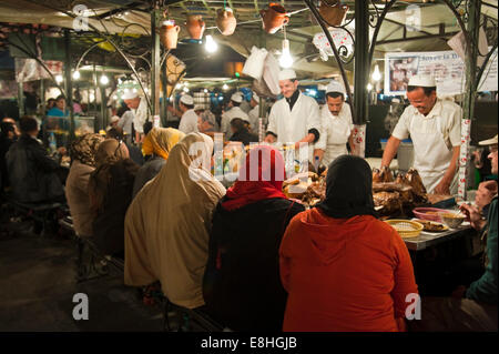 Horizontale Ansicht einer Gruppe von muslimischen Frauen Essen in Place Djemaa el Fna (Djemaa el Fnaa) in Marrakesch in der Nacht. Stockfoto