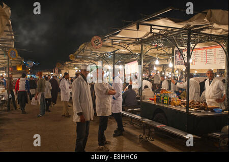 Horizontale Ansicht der Arbeitnehmer an den Ständen in Place Djemaa el Fna (Djemaa el Fnaa) in Marrakesch in der Nacht. Stockfoto