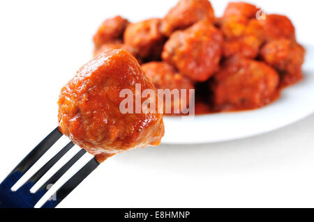 eine Frikadelle in eine Gabel und einen Teller mit einer spanischen Fleischbällchen-Eintopf auf weißem Hintergrund Stockfoto