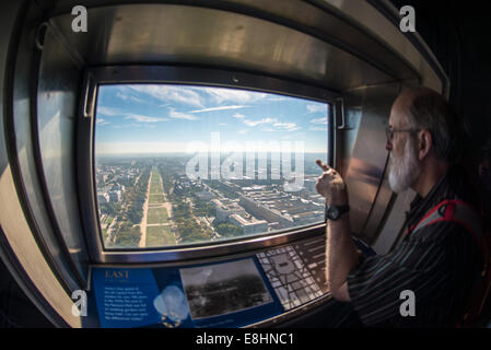 WASHINGTON DC, USA - ein Mann schaut aus dem Fenster nach Osten in Richtung der US Capitol Gebäude von der Spitze des Washington Monument. Das Washington Monument steht an über 555 Fuß (169 Meter) in der Mitte der National Mall in Washington DC. Es wurde 1884 fertiggestellt und umfangreiche Renovierungen in 2012-13 nach einem Erdbeben einige der Struktur beschädigt ist. Stockfoto