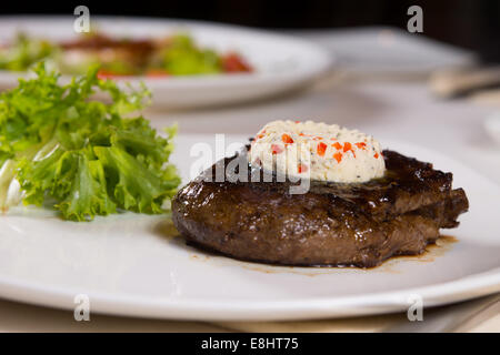 Steak, garniert mit Kräutern Butter auf Platte garniert auf Tisch Stockfoto